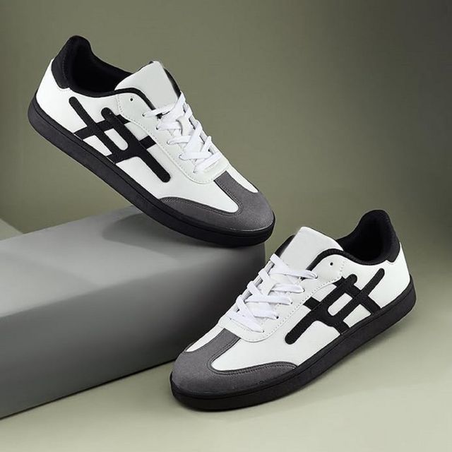 Pair of white and black sneakers on a gray and green gradient background