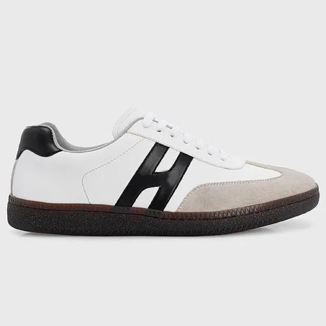 White sneaker with black 'H' logo on a light gray background