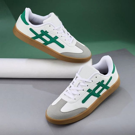 White sneakers with green accents and brown soles on a gray surface.