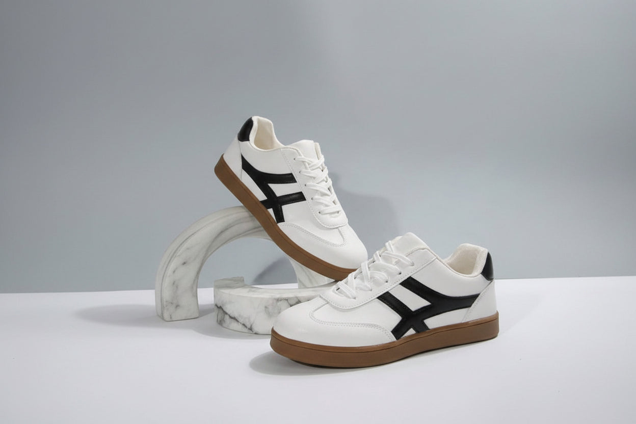 White sneakers with black accents and brown soles on a light gray background