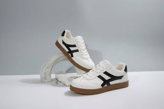 White sneakers with black accents and brown soles on a light gray background